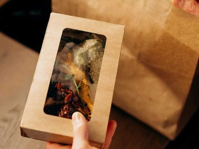 Food in a Carboard Box and a Paper Bag on a Wooden Surface