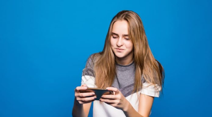 Happy smiling girl with mobile phone playing online games