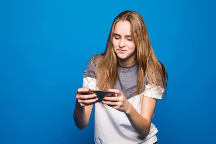Happy smiling girl with mobile phone playing online games