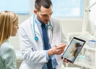 Plastic / Cosmetic Surgeon Consults Woman about Facial Lift Surgery, He Draws Arrows on Digital Tablet Computer Screen, Showing Types of Facelift, Forehead Correcting Procedures Available for Her.