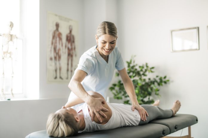 Modern rehabilitation chiropractor worker with woman client for chronic pain
