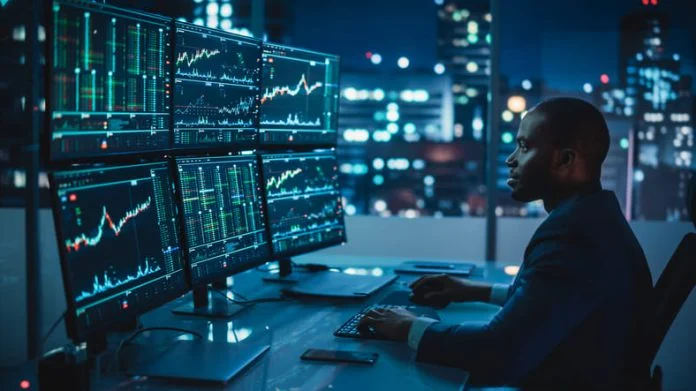 Financial Analyst Working on Computer with Multi-Monitor Workstation with Real-Time Stocks and trading, Commodities and Exchange Market Charts.