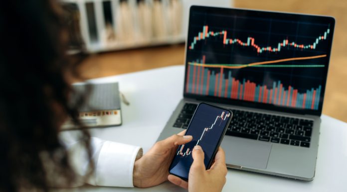 Investment, trading in the stock market. The girl uses a phone and a laptop, looks through the stock market, analyzes stocks, a stock trader assesses risks and possible profits, develops a strategy