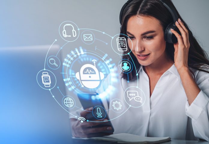 Businesswoman in headphones is holding smartphone with digital interface Businesswoman in headphones is holding smartphone with digital interface with various holograms having online conference call. Robot, smart watch, pie diagram. Office workplace with laptop, notebook