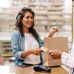Happy female customer paying with a credit card in a retail store