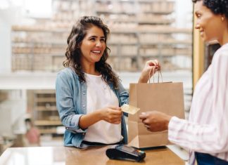 Happy female customer paying with a credit card in a retail store