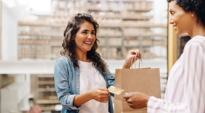 Happy female customer paying with a credit card in a retail store