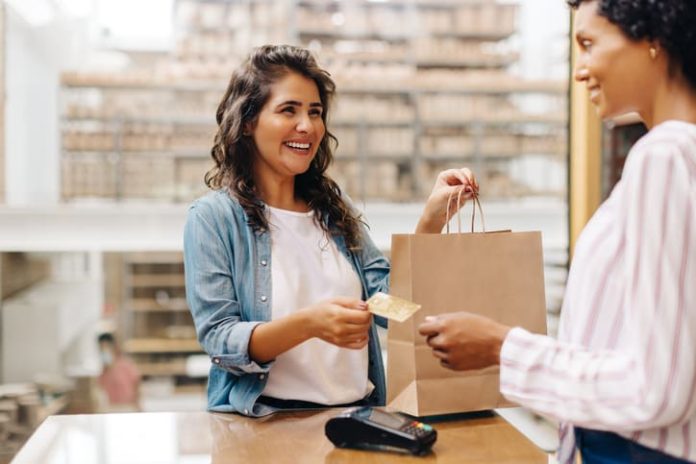 Happy female customer paying with a credit card in a retail store