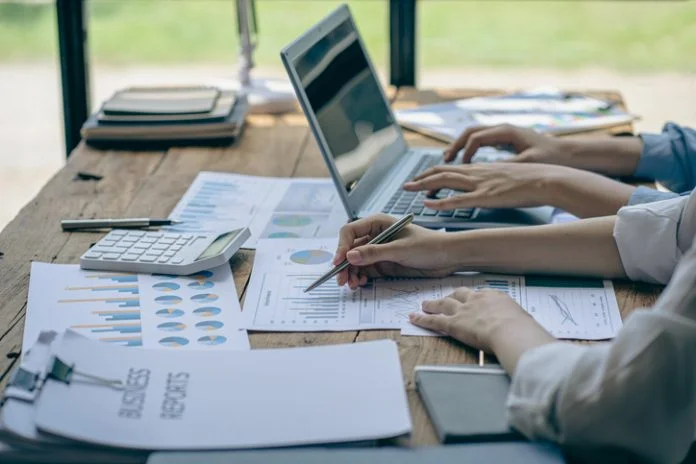 Group of businessmen holding smart pen discussing in group meeting at table in modern office with graph papers and laptop Strategic Planning, Business Collaboration and Brainstorming of Colleagues Building a Successful Journalist and Copywriter Business