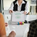 Agent giving life insurance policy to young couple after discussing ULIP