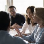 Positive senior business woman giving feedback to her employees while showing radical candour