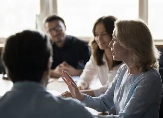 Positive senior business woman giving feedback to her employees while showing radical candour