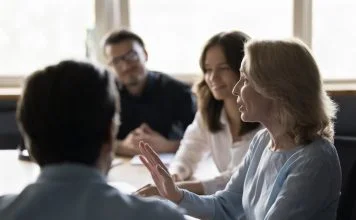 Positive senior business woman giving feedback to her employees while showing radical candour