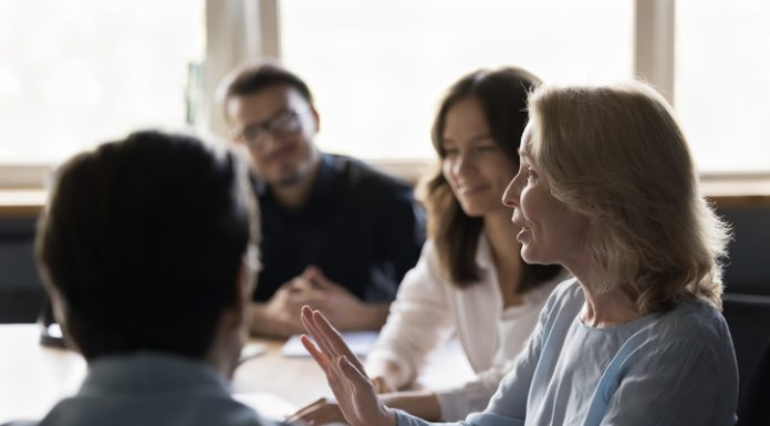 Positive senior business woman giving feedback to her employees while showing radical candour