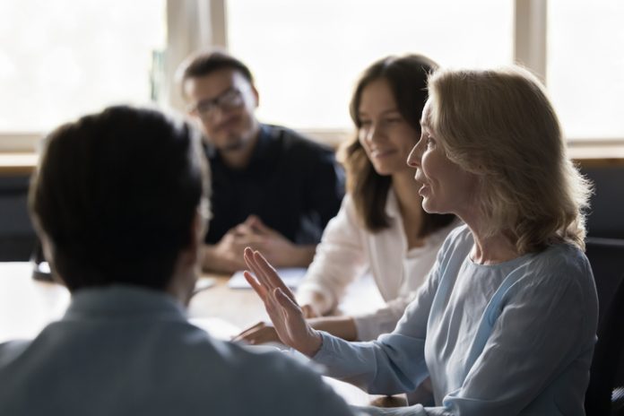 Positive senior business woman giving feedback to her employees while showing radical candour