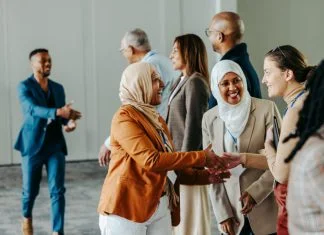 A group of diverse professionals happily exchanging handshakes and greetings at a vibrant business conference, fostering connections and Networkracies opportunities.