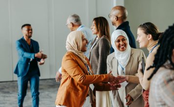 A group of diverse professionals happily exchanging handshakes and greetings at a vibrant business conference, fostering connections and Networkracies opportunities.
