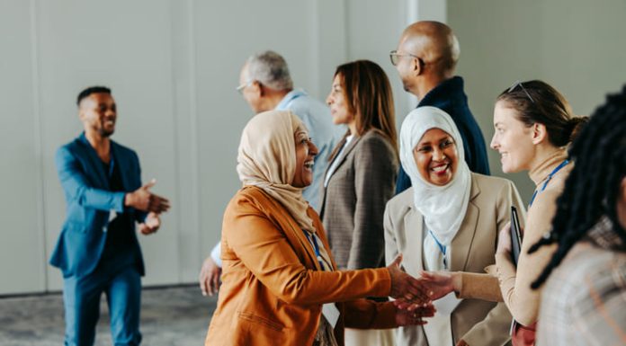 A group of diverse professionals happily exchanging handshakes and greetings at a vibrant business conference, fostering connections and Networkracies opportunities.