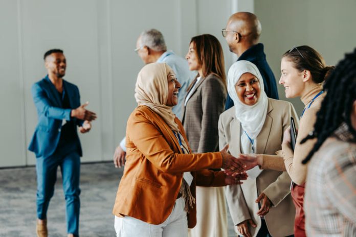 iStock-2174626784 (1) A group of diverse professionals happily exchanging handshakes and greetings at a vibrant business conference, fostering connections and Networkracies opportunities.