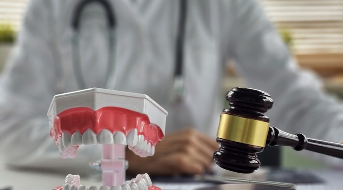 Dental models and gavel on a desk in a professional setting related to dental law or whitening regulation