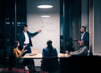 Chief AI Officer with diverse business team in modern office during a late-night meeting. Professional discussion on artificial intelligence strategy. Concept of corporate teamwork, innovation, and AI technology.