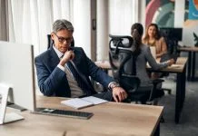 A business leader shifting his focus at his desk in a vibrant office, illustrating productivity and teamwork.