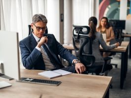 A business leader shifting his focus at his desk in a vibrant office, illustrating productivity and teamwork.