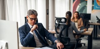A business leader shifting his focus at his desk in a vibrant office, illustrating productivity and teamwork.