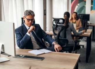 A business leader shifting his focus at his desk in a vibrant office, illustrating productivity and teamwork.