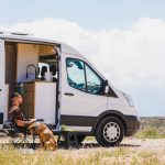 Man relaxing with dog in campervan at gorafe, spain