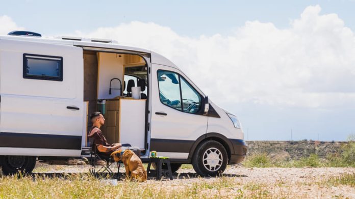 Man relaxing with dog in campervan at gorafe, spain