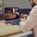 Gambler man sitting at laptop playing online casino roulette on gaming economy