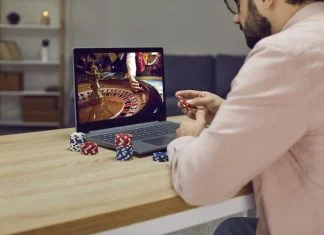 Gambler man sitting at laptop playing online casino roulette on gaming economy