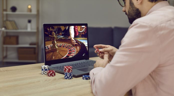 Gambler man sitting at laptop playing online casino roulette on gaming economy