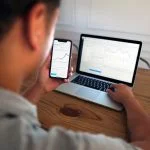 Man using computer and mobile for trading