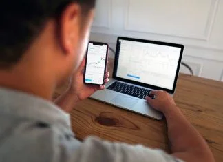 Man using computer and mobile for trading