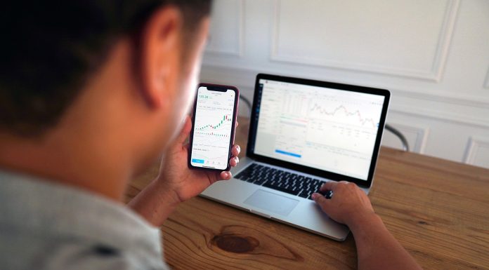 Man using computer and mobile for trading