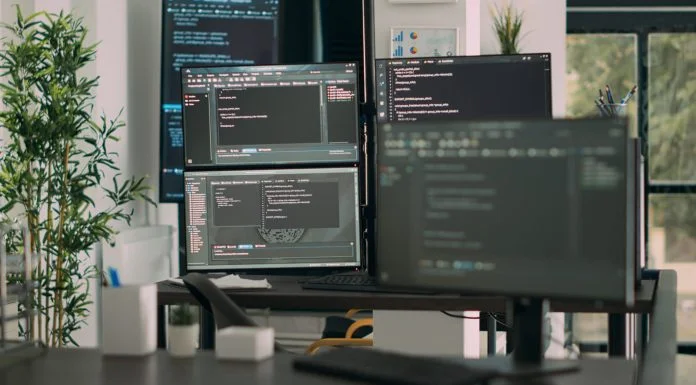 The Downstream Effects of Adopting AI for Coding, and Why Coderabbit Thinks It Can Fix Them CodeRabbit - Desk with multiple screens