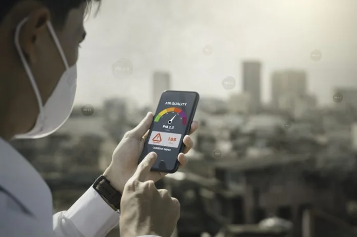 air pollution quality of dust PM 2.5 is toxic and dangerous to health. People use technology smart phone check air quality smog from PM2.5 dust, warning dangerous unhealthy air pollution dust smoke Madeleine Thomson climate change on health risks