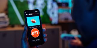 Angliabet Revolutionizes Mobile Betting with Game-Changing App 2.0 Launch online sports betting app, Angliabet with football match bet option visible on screen, sitting indoors.