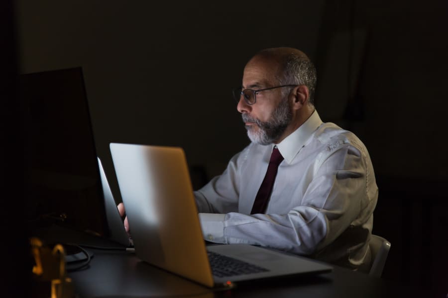 Serious businessman working with laptop and cybersecurity late at night