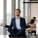 How Spiritual Awareness Can Boost Your Decision-Making in Business Calm businessman in suit meditating on office desk for Spiritual Awareness