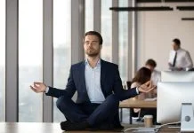 Calm businessman in suit meditating on office desk for Spiritual Awareness