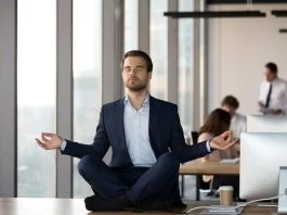 Calm businessman in suit meditating on office desk for Spiritual Awareness