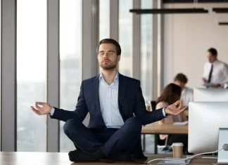 Calm businessman in suit meditating on office desk for Spiritual Awareness