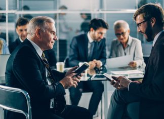 Your Business in Their Pocket: Why Mobile Security Belongs in the Boardroom Business people using mobile devices in the boardroom