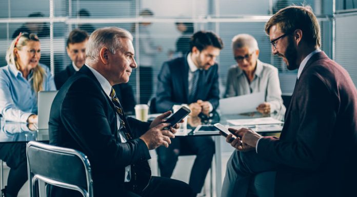 Your Business in Their Pocket: Why Mobile Security Belongs in the Boardroom Business people using mobile devices in the boardroom
