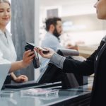 What Can Be Customized in Odoo POS? A Complete Guide Clothing Store: Young Woman At Counter Buys Clothes and paying using Odoo POS