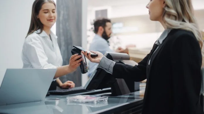 Clothing Store: Young Woman At Counter Buys Clothes and paying using Odoo POS
