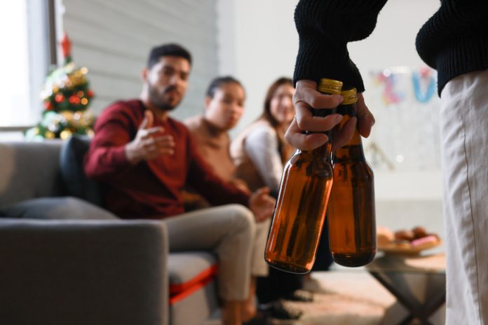 A group of diverse friends celebrates Christmas at home with alcoholic drinks. There is celebration and festivity, and different hands hold glasses with drinks, champagne bottles, wine, and cocktails. Breaking the Cycle: How Parental Support Networks Can Empower Families Battling Alcohol Addiction